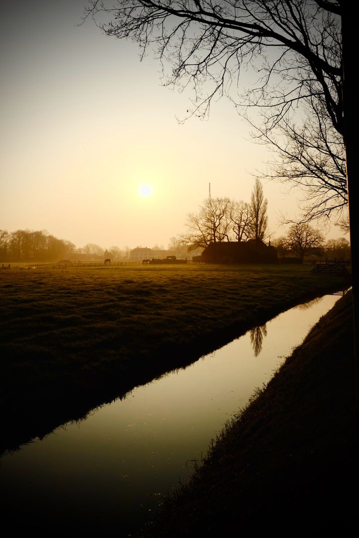 Serene Rural Sunset by Calm River with Farmland - Free Images, Stock Photos and Pictures on Pikwizard.com