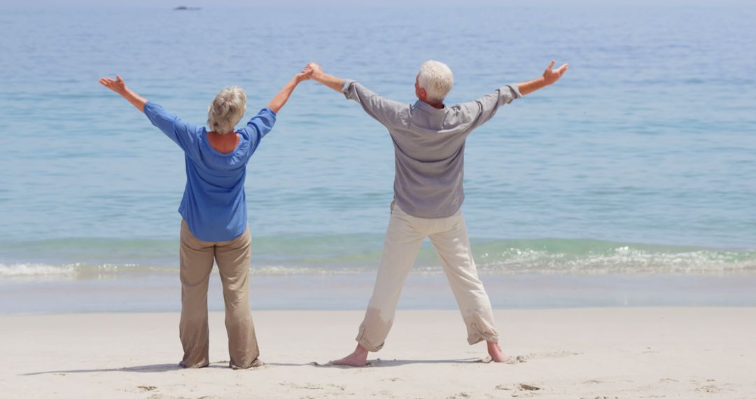 Elderly Couple Enjoying a Beach Day with Arms Raised - Free Images, Stock Photos and Pictures on Pikwizard.com
