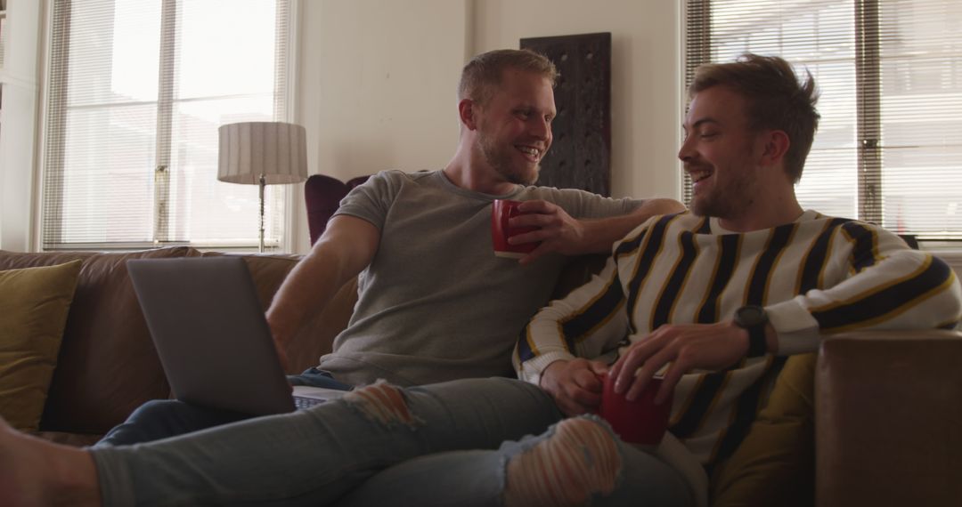 Two Men Relaxing on Couch with Laptop and Coffee - Free Images, Stock Photos and Pictures on Pikwizard.com