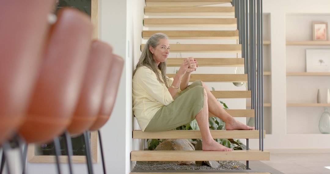 Mature Woman Relaxing on Staircase Holding Coffee Cup