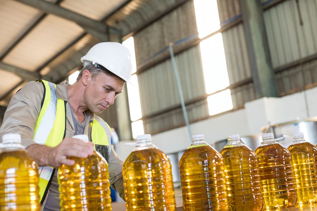 Quality Control Worker Inspecting Bottles in Industrial Warehouse