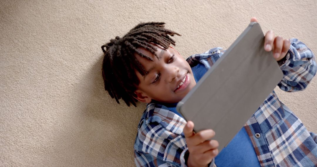 Happy Boy Engaging with Tablet on Carpeted Floor at Home