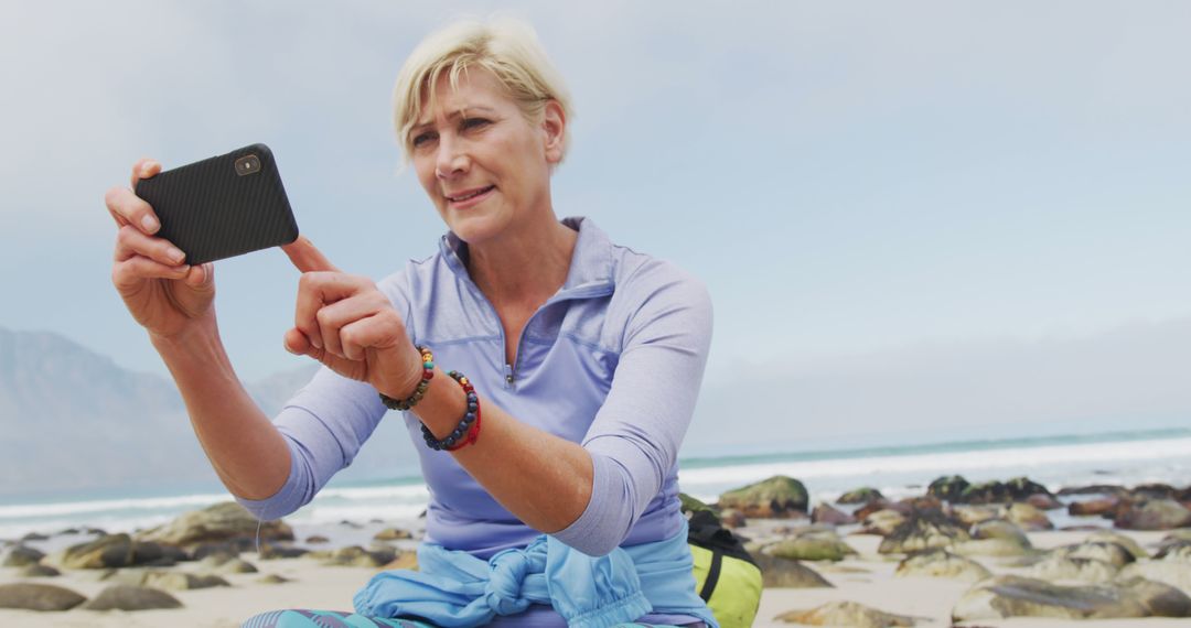 A senior hiker captures memories on her beach trek using her smartphone. - Free Images, Stock Photos and Pictures on Pikwizard.com
