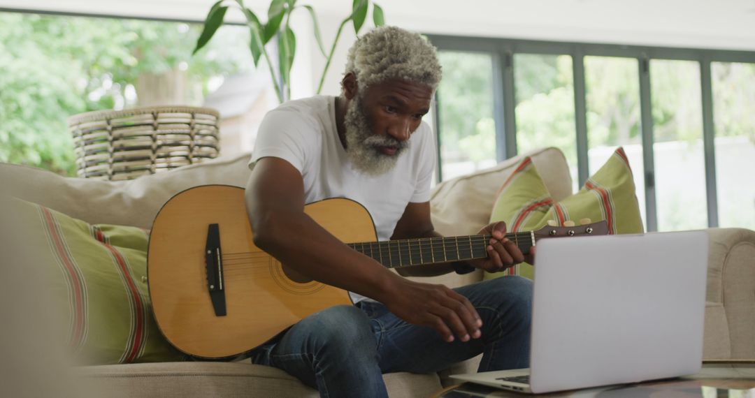 Image of sad african american senior man playing the guitar and using laptop - Free Images, Stock Photos and Pictures on Pikwizard.com