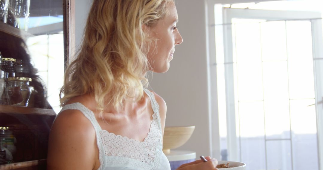 Woman Enjoying Cereal in Bright Kitchen with Morning Light - Free Images, Stock Photos and Pictures on Pikwizard.com