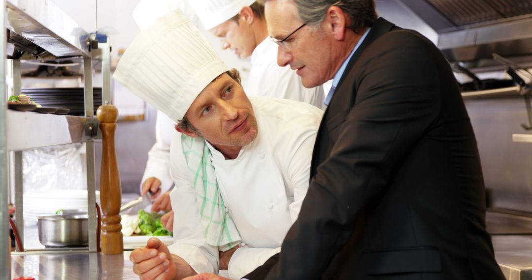 Chef Discussing with Businessman in Busy Restaurant Kitchen - Free Images, Stock Photos and Pictures on Pikwizard.com