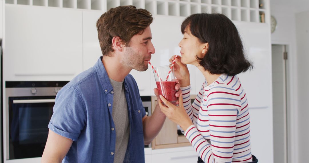 Image of happy diverse couple drinking juice with straws in kitchen - Free Images, Stock Photos and Pictures on Pikwizard.com