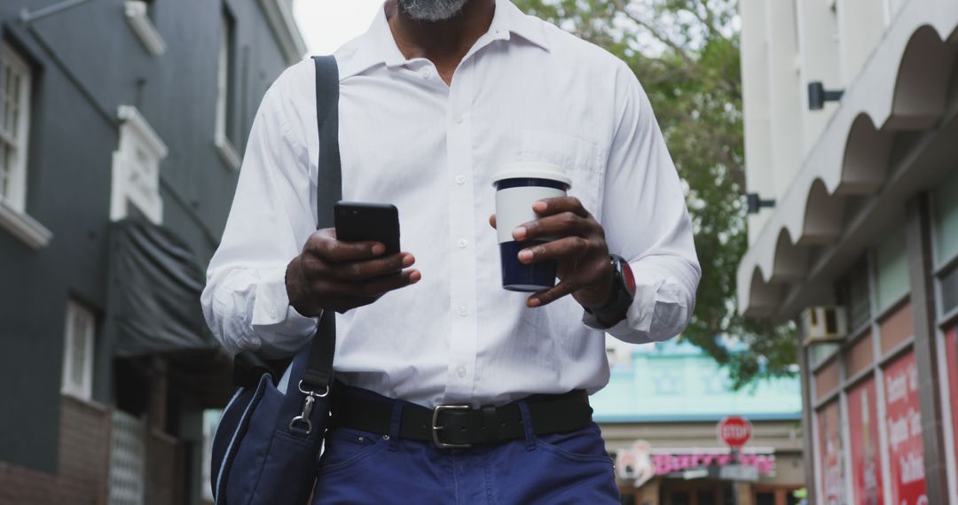 Businessman Walking on Street Using Smartphone and Holding Coffee - Free Images, Stock Photos and Pictures on Pikwizard.com