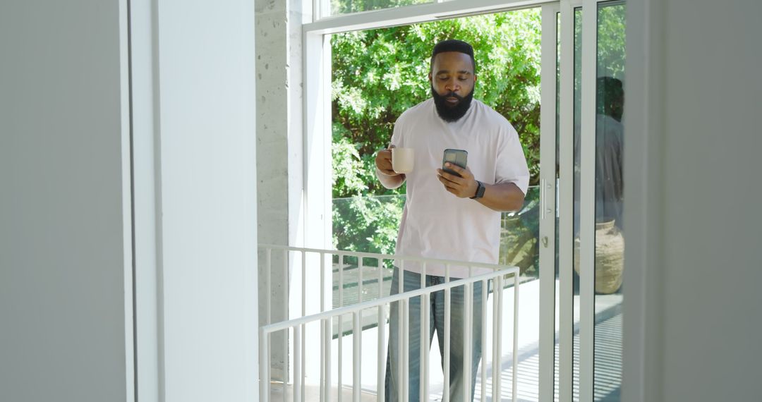 Mid Adult Man Relaxing on Balcony with Coffee and Smartphone