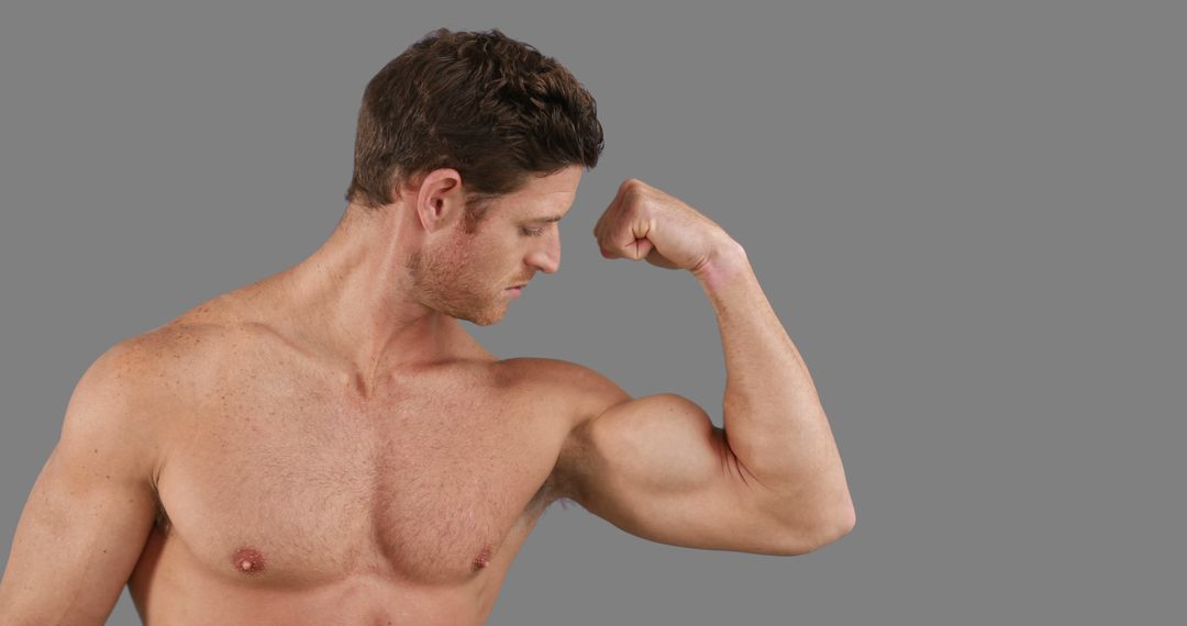 Muscular Man Flexing Bicep on Gray Background - Free Images, Stock Photos and Pictures on Pikwizard.com