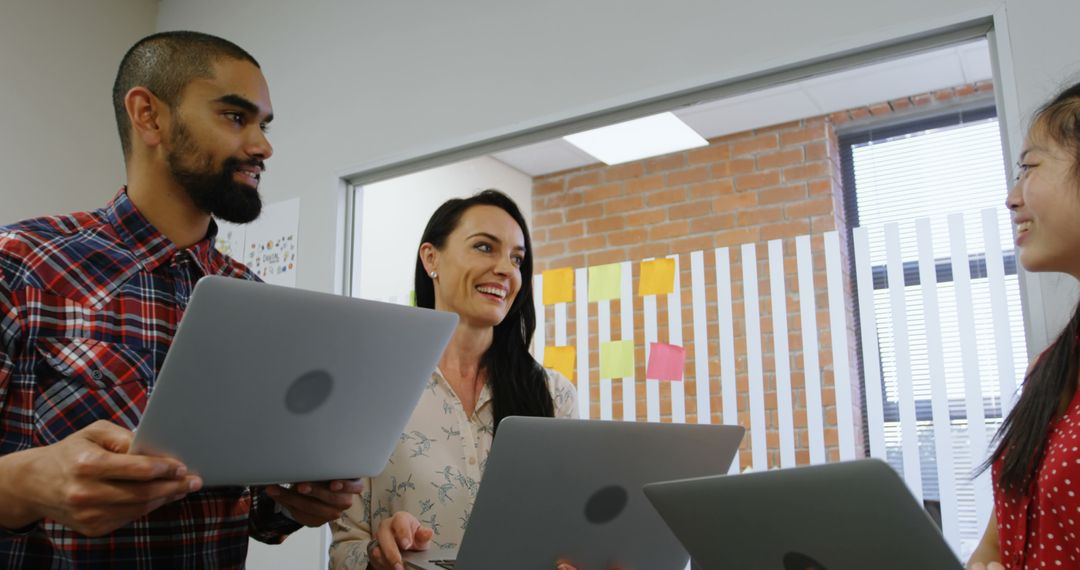 Diverse Team Collaborating in Office with Laptops