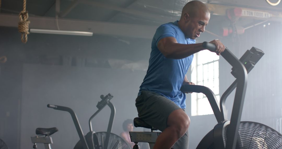 Focused Man Exercising on Stationary Bike in Gym - Free Images, Stock Photos and Pictures on Pikwizard.com