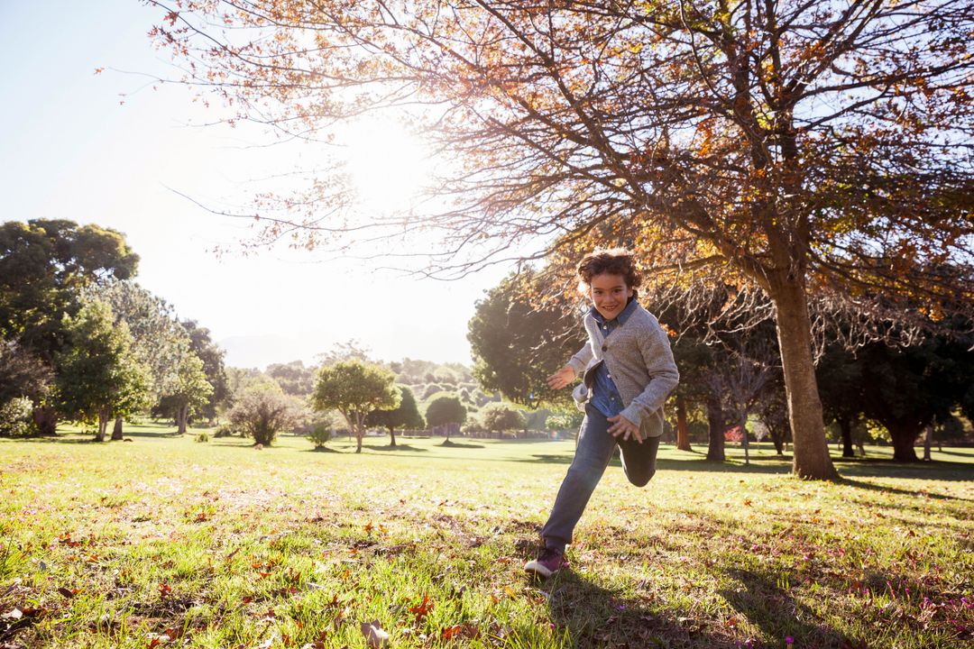 Joyful Child Running Through Sunlit Park in Autumn