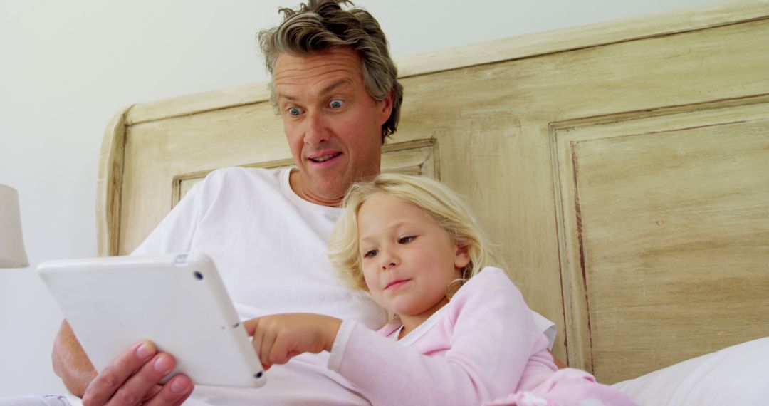 Father and Daughter Using Tablet Together in Bed - Free Images, Stock Photos and Pictures on Pikwizard.com