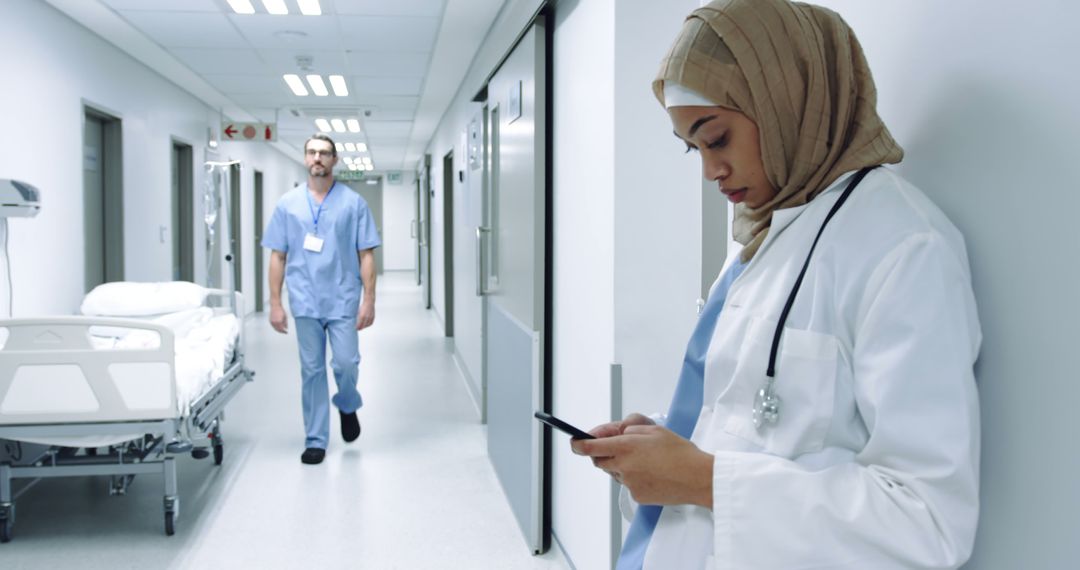 Serious Female Doctor in Hijab Using Smartphone in Hospital Corridor - Free Images, Stock Photos and Pictures on Pikwizard.com