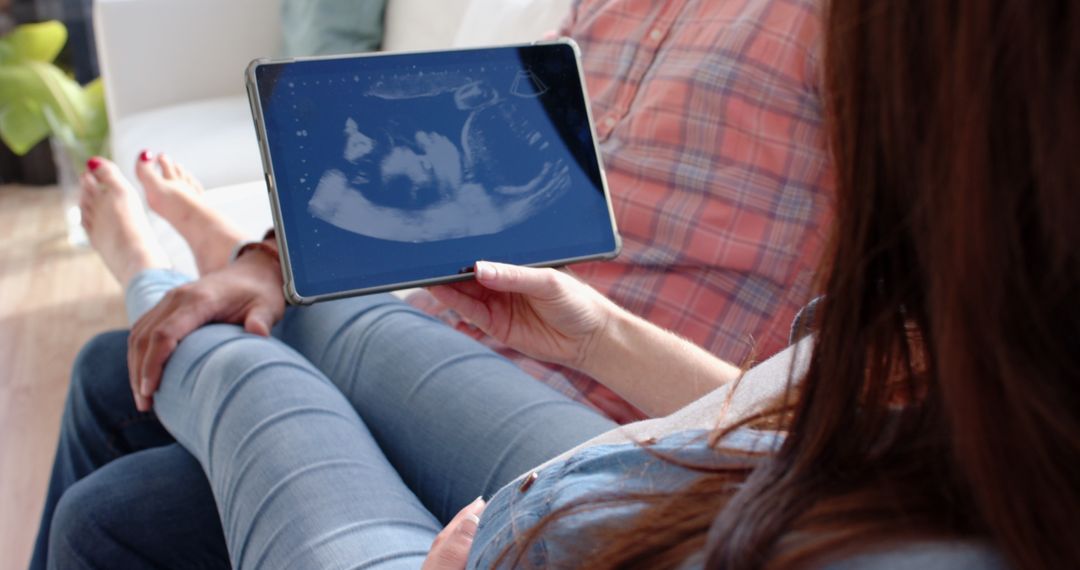 Expectant Couple Viewing Ultrasound on Tablet at Home