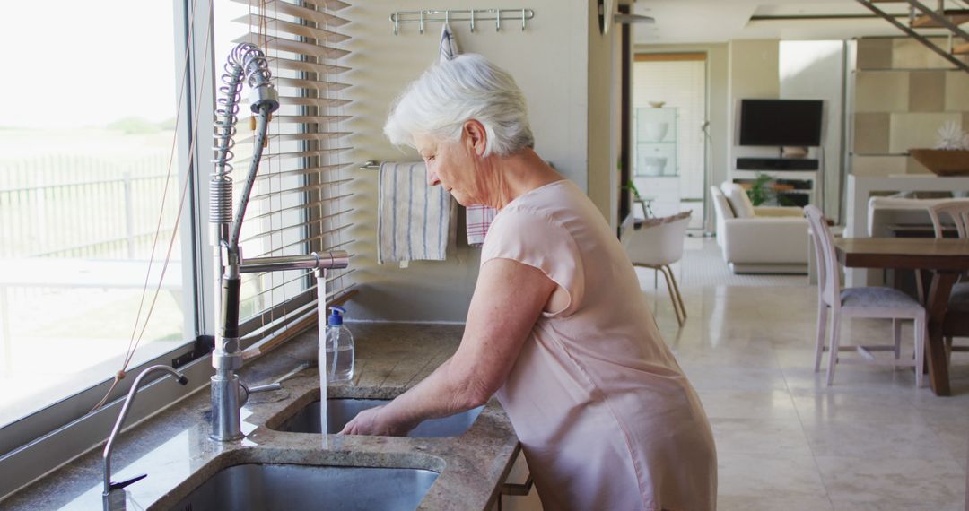 Senior Woman Washing Hands at Kitchen Sink in Modern Home - Free Images, Stock Photos and Pictures on Pikwizard.com