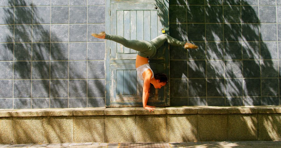 Woman Practicing Handstand Against Wall Outdoors - Free Images, Stock Photos and Pictures on Pikwizard.com