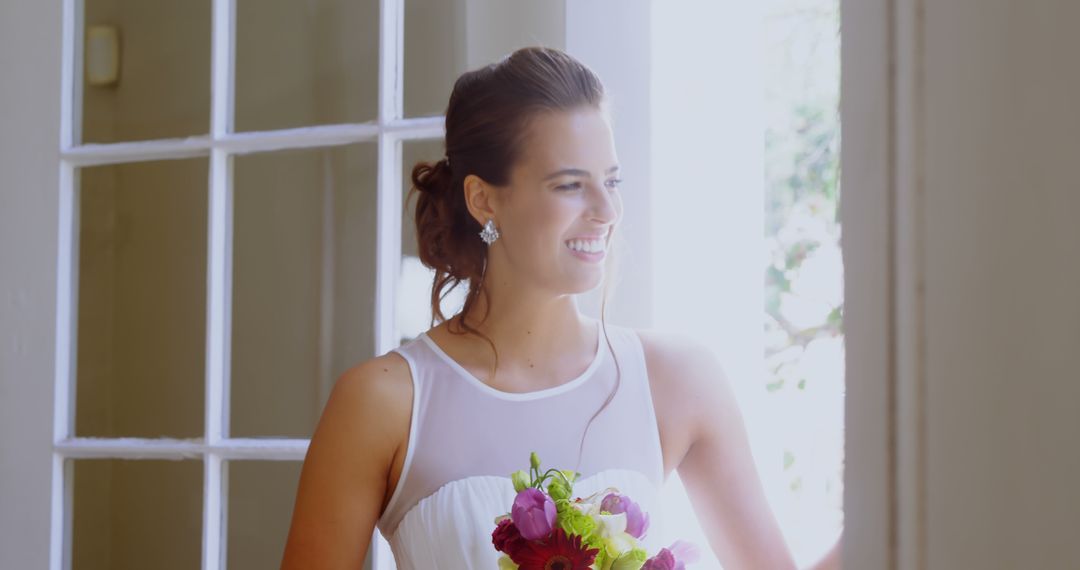 Smiling Bride Holding Bouquet Next to Sunlit Window - Free Images, Stock Photos and Pictures on Pikwizard.com