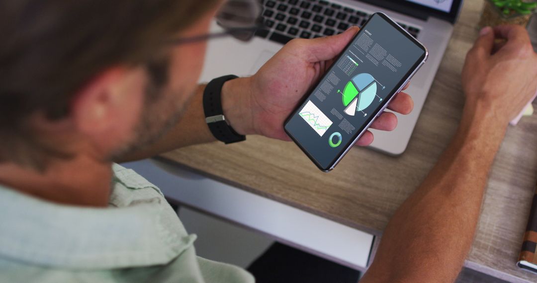 Man Analyzing Statistics on Smartphone at Work Desk
