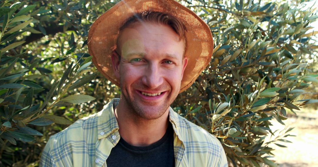 Smiling Man in Sunny Orchard with Hat Enjoying Nature