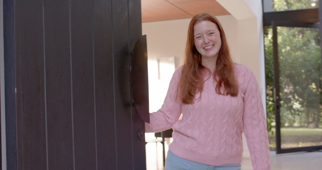 Smiling woman welcoming at home entrance with open door