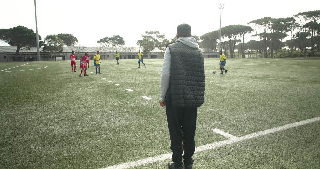 Coach Observing Soccer Players During Training on Sunny Field