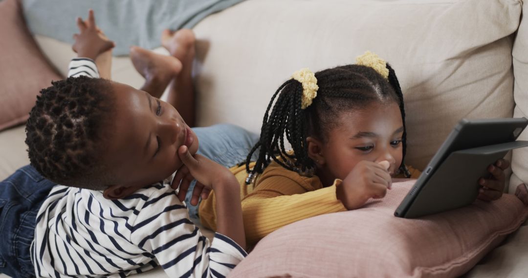 Two Children Relaxing on Couch with Digital Tablet - Free Images, Stock Photos and Pictures on Pikwizard.com