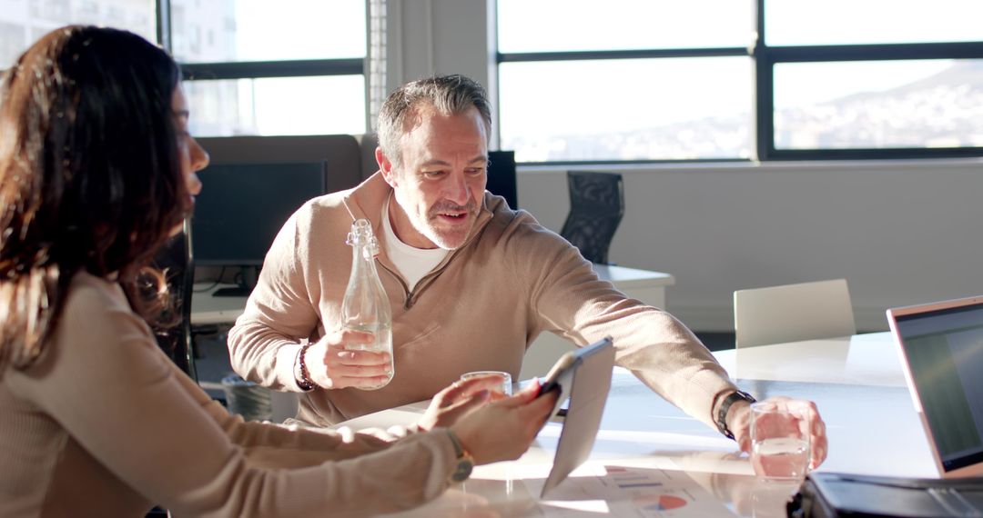 Diverse team collaborating over laptop charts in bright modern office