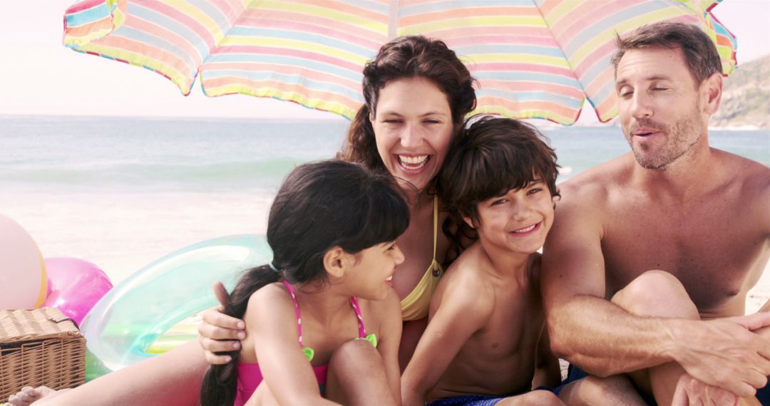 Happy family enjoying beach vacation together under umbrella - Free Images, Stock Photos and Pictures on Pikwizard.com