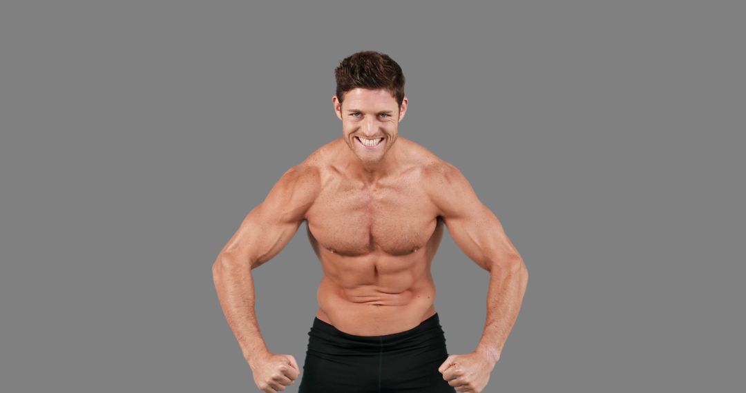 A muscular Caucasian man flexes his biceps and smiles confidently, with copy space - Free Images, Stock Photos and Pictures on Pikwizard.com