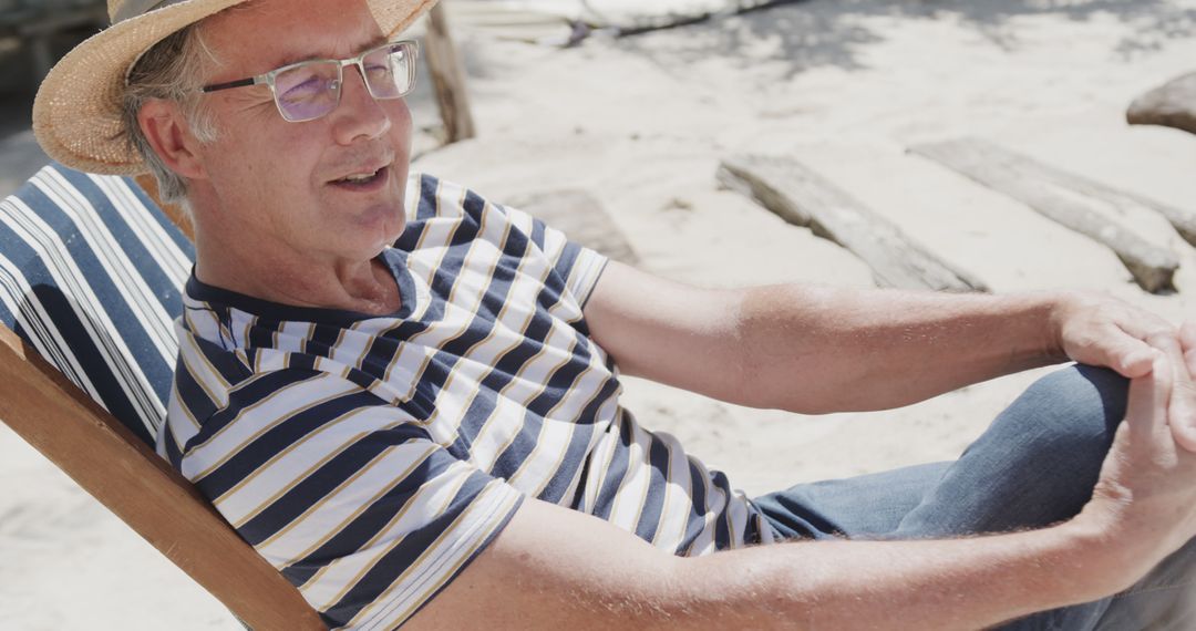 Relaxed Man in Straw Hat Sitting on Beach Chair by Sunny Beach - Free Images, Stock Photos and Pictures on Pikwizard.com