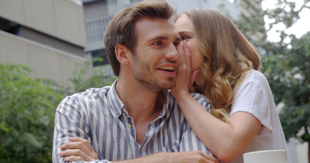 Young Woman Whispering to Smiling Man Outdoors - Free Images, Stock Photos and Pictures on Pikwizard.com