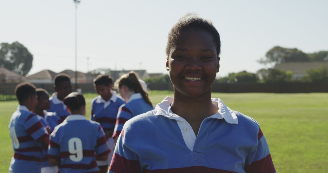 Young Athlete Smiling at Rugby Field, Team in Background - Free Images, Stock Photos and Pictures on Pikwizard.com