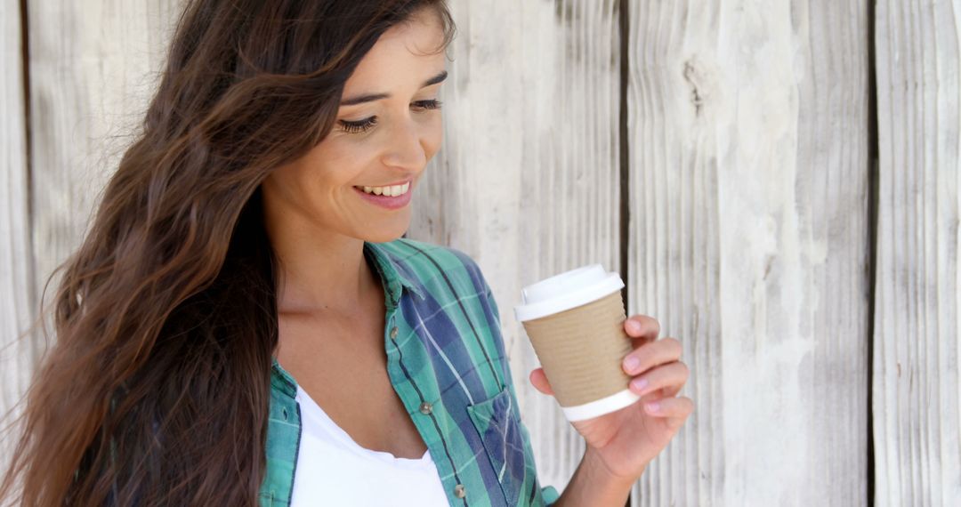 Smiling Young Woman Enjoying Coffee Outdoors in Casual Clothing - Free Images, Stock Photos and Pictures on Pikwizard.com