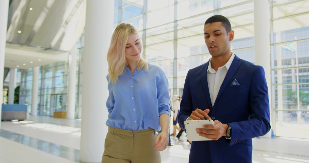 Business Colleagues Discussing Project on Tablet in Modern Office Atrium