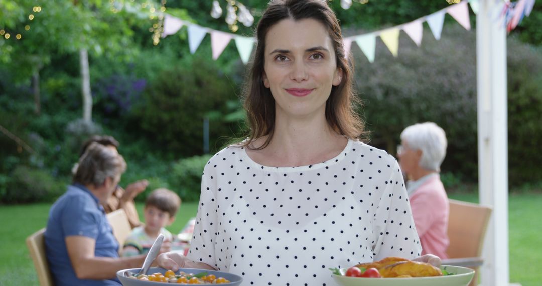 Smiling Woman Holding Bowls of Fresh Food at Outdoor Family Gathering - Free Images, Stock Photos and Pictures on Pikwizard.com