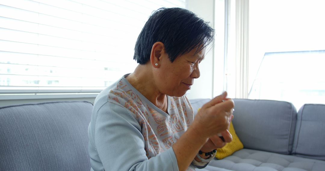 Older Woman Knitting by the Window on a Comfortable Sofa - Free Images, Stock Photos and Pictures on Pikwizard.com