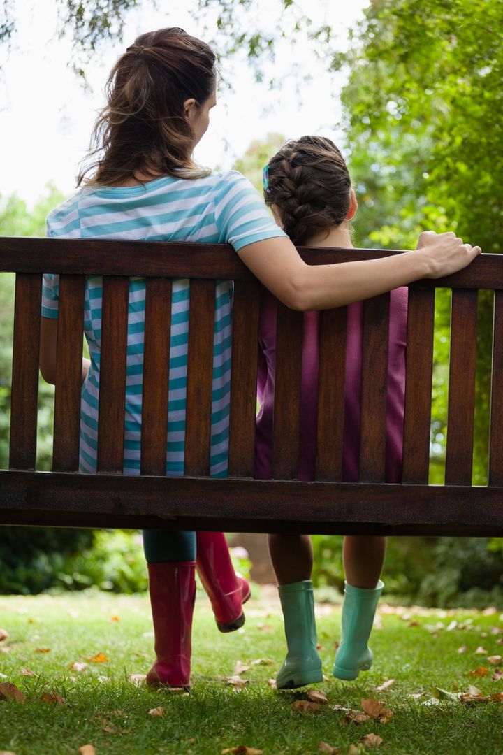 Rear view of girl and woman sitting on wooden bench - Free Images, Stock Photos and Pictures on Pikwizard.com