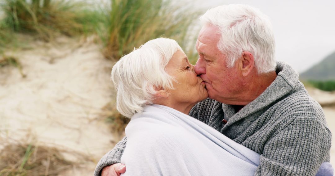 An elderly couple shares a tender beachside kiss, symbolizing enduring love. - Free Images, Stock Photos and Pictures on Pikwizard.com