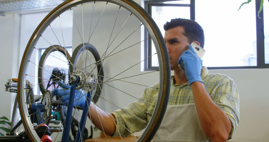 Bicycle Mechanic Repairing Wheel While Talking on Phone in Workshop - Free Images, Stock Photos and Pictures on Pikwizard.com