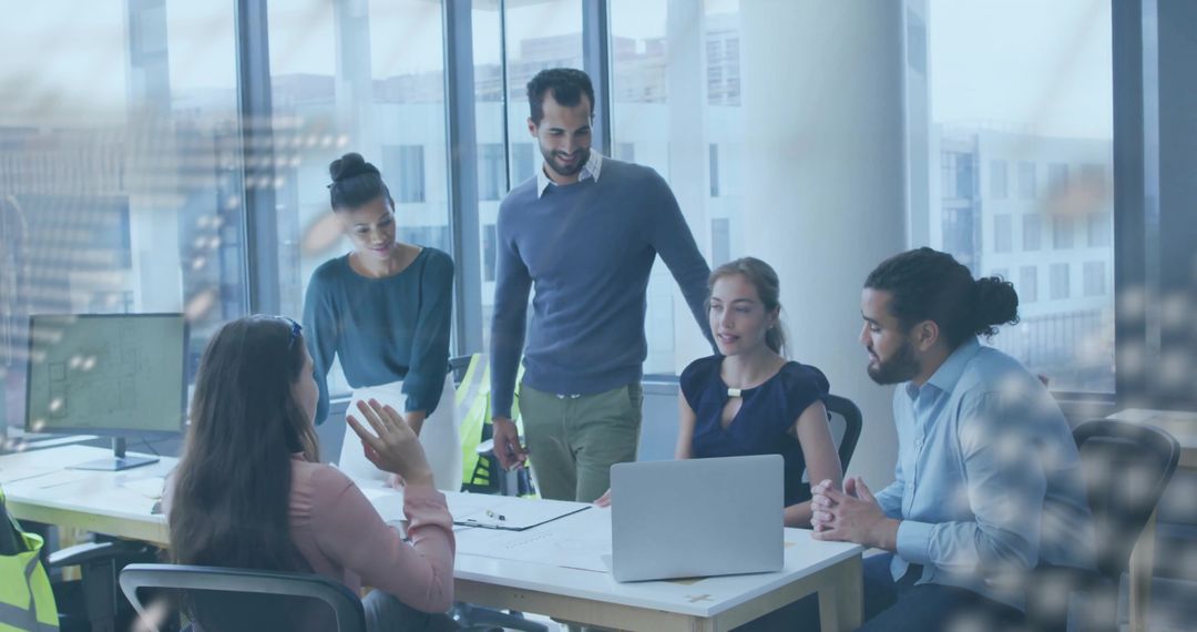 Team Collaborating with Laptops and Documents in Modern Office