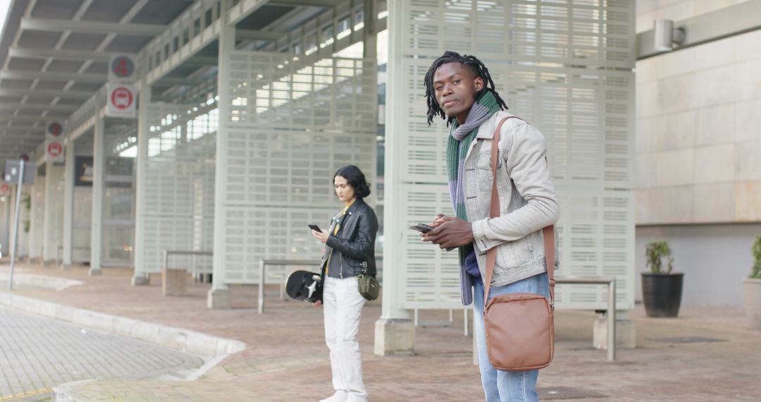 Diverse Commuters Standing Under Transit Canopy Checking Smartphones During Urban Commute