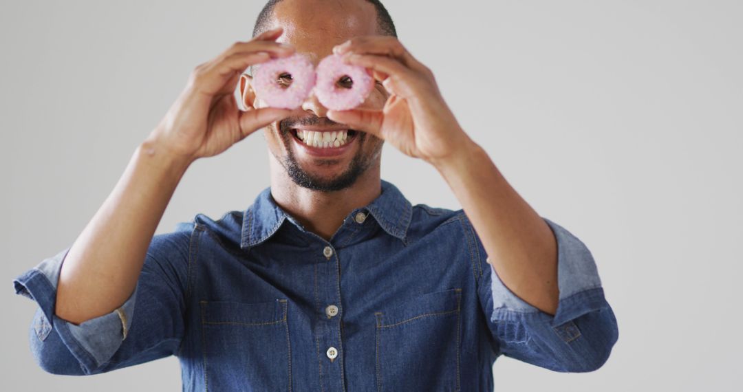 Man Holding Pink Donuts Over His Eyes and Smiling Joyfully - Free Images, Stock Photos and Pictures on Pikwizard.com