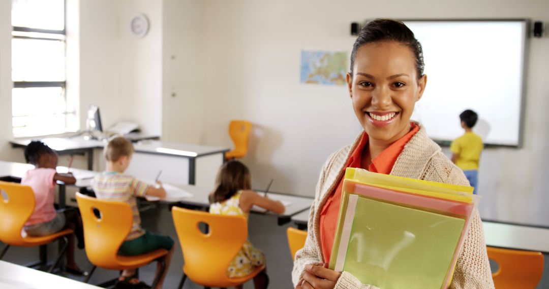 Smiling Teacher Holding Folders in a Classroom - Free Images, Stock Photos and Pictures on Pikwizard.com