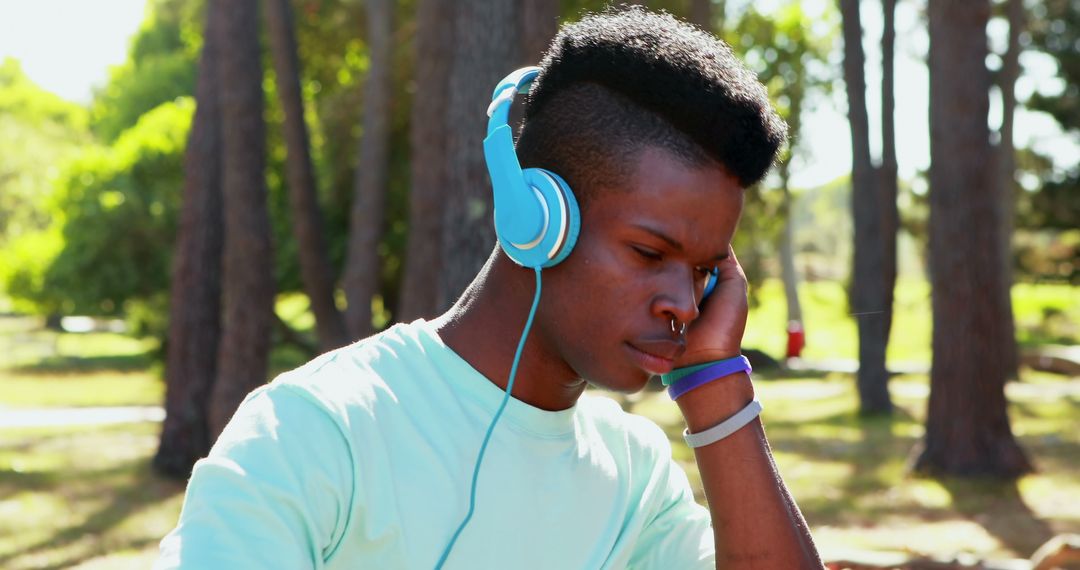 Young Man Listening to Music Outdoors with Blue Headphones - Free Images, Stock Photos and Pictures on Pikwizard.com