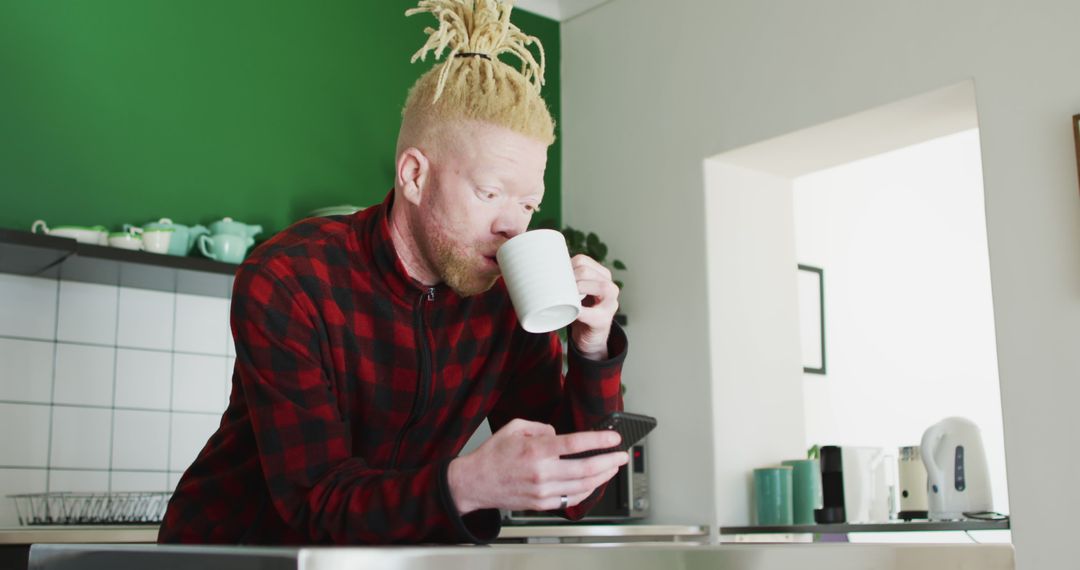 Man with Dreadlocks Drinking Coffee and Using Smartphone in Modern Kitchen - Free Images, Stock Photos and Pictures on Pikwizard.com