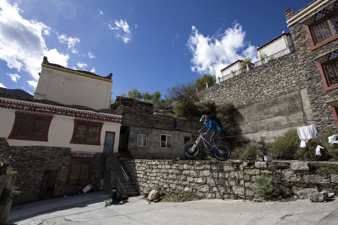 Mountain Biker Performing Stunt in Traditional Village - Free Images, Stock Photos and Pictures on Pikwizard.com