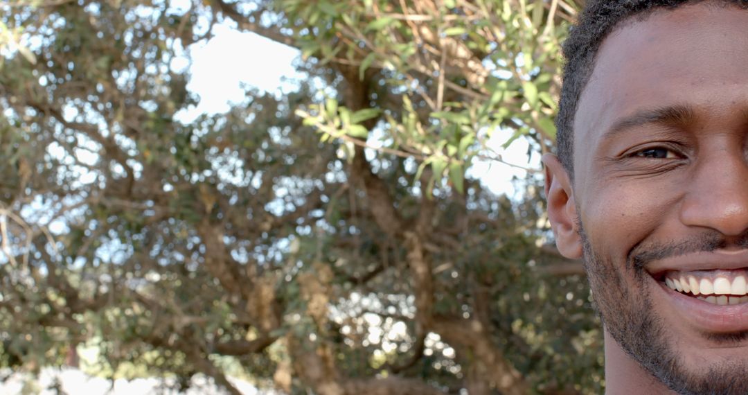 Smiling Man Enjoying Sunny Day Outdoors with Trees in Background