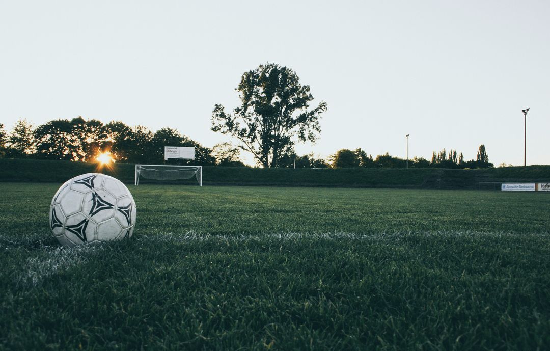 Sunset Soccer Ball on Grass with Goal in Distance Low Angle Athletic Field